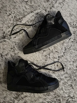 Yohji Yamamoto Y3 hightop sneakers - Yohji Yamamoto Y3 hightop sneakers  Ingen synlig storleksetikett men uppskattas vara storlek 38eu. Tillverkade av en mängd olika material, främst läder och mocka, med läderfoder och innersulor.  De är använda men fortfarande i gott skick med minimalt slitage på sulorna och fodret är fortfarande helt intakt.