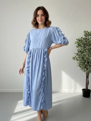 Ljusblå långklänning med volang - Ljusblå långklänning med rund hals och puffiga kortärmar. Klänningen har dekorativa volanger längs ärmarna och framtill, vilket ger en lekfull och trendig look. Passar även till gravida kvinnor.