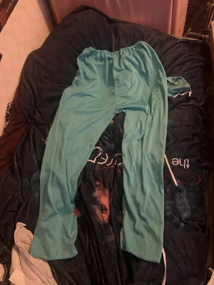 Turkos scrubs-set med dragsko - Säljer ett turkost scrubs-set ”halloween kostym” med byxa och topp. Byxan har elastisk midja med dragsko och raka ben, medan toppen har korta ärmar och enkel design. Perfekt för dig som vill ha bekväma arbetskläder i mjukt material.