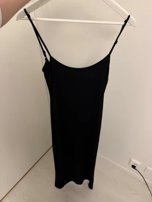Svart tight klänning från Berskha  - Svart tight klänning med urringning där bak, storlek s.