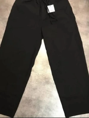 Svarta mjukisbyxor Pull&Bear L - Säljer ett par svarta mjukisbyxor från Pull&Bear i storlek L. Byxorna har bred passform, resår i midjan med dragsko och är tillverkade i ett mjukt material. Perfekta för chill dagar eller när du vill ha det bekvämt.