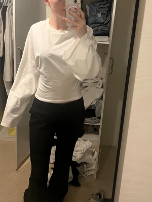 Vit långärmad topp med vida ärmar - Säljer en vit långärmad topp med vida ärmar och rund hals. Toppen har en slim passform i midjan och är tillverkad i ett mjukt bomullsliknande material. Perfekt för dig som gillar minimalistisk och clean stil. Aldrig använd har lappen kvar 
