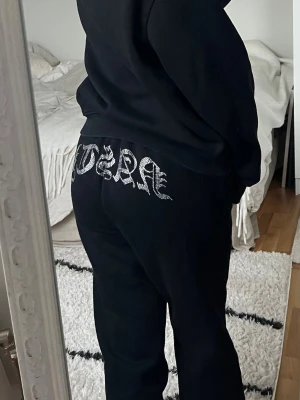 Hidden cult - Svarta Hidden Cult mjukisbyxor med elastisk midja och snörning framtill. Storlek S i fint skick. På baksidan finns en stor strassdekor med texten 'NASTY' i gotisk stil. Byxorna har en loose passform och är tillverkade i mjukt bomullsmaterial, perfekta för chill dagar. Har även tillhörande hoodie i en annan annons 🖤