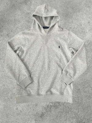 Ralph Lauren Hoodie - Grå Ralph Lauren Hoodie! Säljer nu denna Ralph Lauren Hoodie. Storlek M. Väldigt fint skick. Använda ungefär 3-4 gånger. Inga fläckar! Det finns snören som följer med men jag har valt att ta bort de men man kan ha de som man vill😊 Hör av dig vid funderingar✅