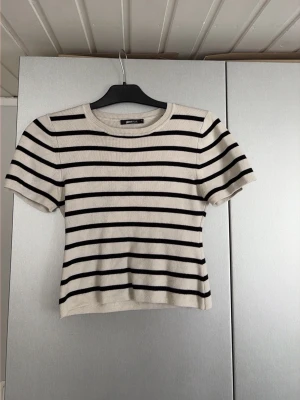 Randig croppad topp Gina Tricot - Säljer en croppad topp från Gina Tricot i vit med svarta horisontella ränder. Toppen har korta ärmar, rund halsringning och är gjord i mjuk bomullsmix. Storlek L men sitter tight på mig som vanligtvis bär s/m💕