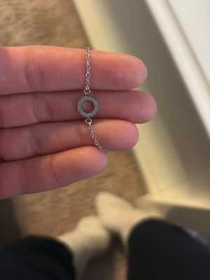 Silver armband från Edblad  - Ett stilrent armband i silverfärg med en tunn kedja och en enkel cirkelformad berlock. Perfekt för dig som gillar minimalistiska smycken och vill ha något diskret men snyggt. Armband är i äkta silver och designen är modern och enkel. Aldrig använt