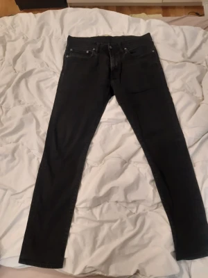 Svarta Levis jeans 512 - Säljer ett par svarta Levis 512 jeans med klassisk femficksdesign. Jeansen har normal midja och dragkedja med knapp framtill. Perfekta för dig som gillar en stilren och enkel look, med snygg patina. 