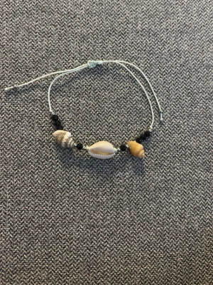 Snäckarmband med svarta pärlor - Snyggt armband med tre olika snäckor i naturfärger och svarta pärlor på vit justerbar tråd. Perfekt accessoar för en strandig och avslappnad stil. Armbandet har en bohemisk vibe och passar till många outfits speciellt på sommarn. Köpte när jag var i Grekland 2022 och insett att jag köpte två likadana.