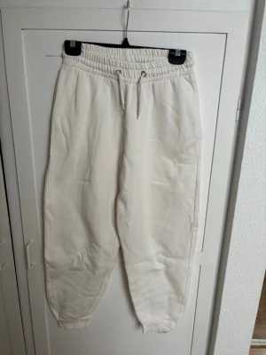 Beiga mjukisbyxor med dragsko - Säljer ett par beiga mjukisbyxor med elastisk midja och dragsko. Byxorna har ribbade muddar vid benslut och är tillverkade i ett mjukt och tjockt material som känns riktigt skönt. Perfekta för chill dagar och avslappnade outfits.