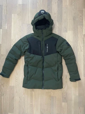 Sail Racing dunjacka – grön/svart – mycket bra skick - Säljer en Sail Racing dunjacka i mycket bra skick. Varm, stilren och funktionell jacka som passar perfekt för höst och vinter ❄️  Jackan har: • Justerbar huva • Dragkedjefickor • Vind- och vattenavvisande material • Snygg grön färg med svarta detaljer • Diskret Sail Racing-logga på bröstet och huvan 	•	Märke: Sail Racing 	•	Typ: Dunjacka / vinterjacka 	•	Skick: Mycket bra skick, sparsamt använd 	•	Passform: Regular 💰 Pris: 1499 kr 📦 Skickas snabbt 💬 Hör av dig om du vill ha mått eller fler bilder