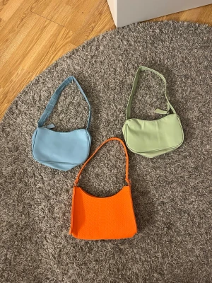 Färgglada axelväskor -  Säljer dessa tre färgglada handväskor. Den gröna och den blåa är likadana, i ett plast skinn material. Den orangea har ett orm skinn mönster på och är i ett tyg material. De har inga innerfickor. De är i väldigt bra skick då de aldrig använts. De alla tre är ifrån shein. Den orangea är inköpt för 50kr, medans den blåa och gröna är inköpta för 30kr styck. Alla tre väskor kan man få för 50kr, annars kostar de 20kr styck💕