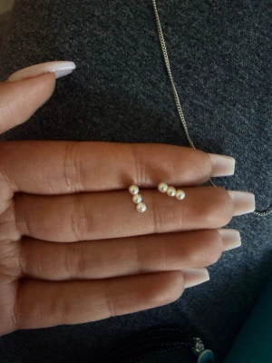 Örhängen med små vita pärlor - Säljer ett par stilrena örhängen med tre små vita pärlor på rad. Örhängena har stift i silverfärgad metall och en minimalistisk design som passar till många olika looks. Perfekta för dig som gillar enkla men snygga accessoarer.