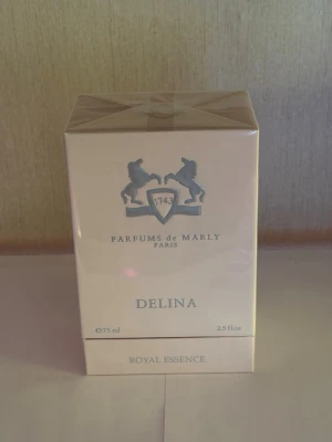 Parfums de Marly Delina 75ml - Lyxig parfym från Parfums de Marly i modellen Delina. Kommer i en elegant ljusrosa kartong med silverdetaljer och logga med två hästar. Flaskan rymmer 75 ml och tillhör Royal Essence-serien. Perfekt för dig som gillar exklusiva dofter.