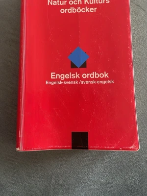 Engelsk ordbok Natur och Kultur - Engelsk ordbok från Natur och Kultur med röd plastpärm. Innehåller engelska-svenska och svenska-engelska översättningar, över 63 500 ord och fraser. Praktisk och enkel att använda, perfekt för studier eller resor.