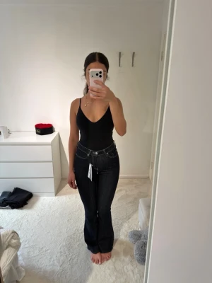 Mörkblå bootcut jeans från Gina Tricot - Säljer ett par mörkblå bootcut jeans från Gina Tricot med klassiska kontrastsömmar och femficksdesign. Jeansen har hög midja och raka ben med lätt utsvängning nertill. Perfekta för dig som gillar en tidlös och snygg look.