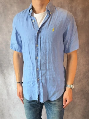Ljusblå Kortärmad Ralph Lauren Linneskjorta- Stl S, Classic Fit - Riktig snygg kortärmad Ralph Lauren linneskjorta, perfekt till sommaren! 🏖️🌊 | Mycket bra skick: 9,2/10, utan defekter  | Stl: S |  Modellen är 177cm och väger 74kg | Billigare pris vid köp av bundle 😉Hör av dig vid frågor // Galgen 🫡 