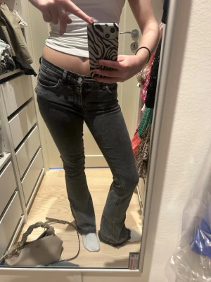Svarta bootcut jeans med slitna kanter - Snygga svarta jeans med bootcut passform och slitna kanter längst ner. Jeansen har klassisk femficksdesign, knapp och dragkedja framtill samt en mörk tvätt som ger en cool vibe. Perfekta för dig som gillar en avslappnad men trendig stil.