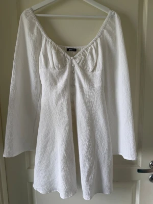 Vit kort klänning med knappar - Superfin vit kort klänning från Gina Tricot med långa ärmar och knappar framtill. Använda endast en gång 