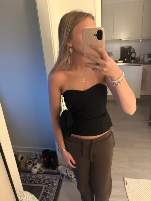 Svart axelbandslös topp från Bik Bok -  jättesöt svart axelbandslös topp från Bik Bok! med rosett på sidan🥰 helt oanvänd med prislappen kvar.