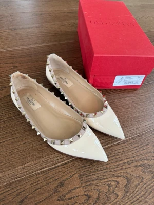 Valentino Rockstud ballerinaskor  - Kollar intresset på mina såå snygga vita valentino rockstud ballerinaskor, perfekt nu till sommaren!!skorna är använda en gång på studenten så fortfarande fint skick förutom de få defekterna som blivit på insidan av skorna (syns inte när man har dom på sig) storlek 37/5 men passar mig som har storlek 38 i skor! Kvitto finns samt alla tillbehör, köpta för 8500kr, priset är diskuterbart💕💕