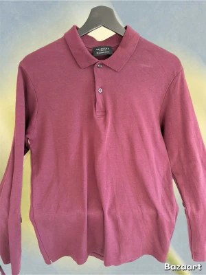 Långärmad polo i mörkrosa bomull - Långärmad polo från Selected Homme i en snygg mörkrosa nyans. Klassisk krage med två knappar framtill och tillverkad i mjuk bomull. Perfekt för en stilren och avslappnad look.