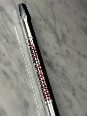 Benefit Precisely, My Brow Pencil 2.5 - Slim ögonbrynspenna från Benefit i färgen 2.5, perfekt för att skapa naturliga och definierade bryn. Pennan har en tunn spets för exakt applicering och kommer i en snygg silver- och svart design.