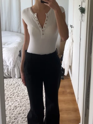 Vit ribbad body med knappar - Snygg vit ribbad body med guldiga knappar från Zara Perfekt att styla med både jeans och kostymbyxor.