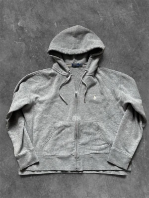 Grå zip hoodie från Polo Ralph Lauren - Snygg grå hoodie🧼 med dragkedja från Polo Ralph Lauren. Klassisk design med huva 🐧 och dragsnören, två stora fickor och den klassiska Ralph Lauren broderade loggan på bröstet. Tillverkad i mjuk bomullsblandning för maximal komfort. Passar även S 👀Är även öppen för era pris förslag 😄
