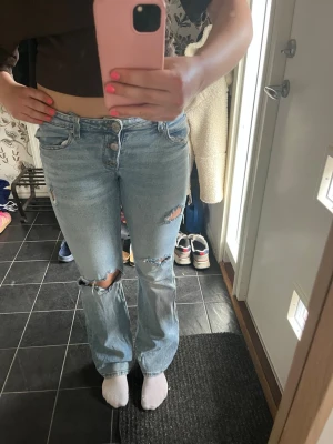 Ljusblå jeans från Gina Tricot - Snygga ljusblå jeans från Gina Tricot med slitna detaljer och hål på benen. Perfekta för en trendig och avslappnad stil. Säljer då dem tyvärr blivit för små för mig! De har en liten fläck längst ner på höger ben, absolut inget man lägger märke till men därav det lite billigare priset! Skicka gärna prisförslag💛