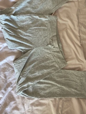 Grå mjukisbyxor lågmidja - Snygga och bekväma grå mjukisbyxor med dragsko i midjan. Byxorna har en avslappnad passform och är tillverkade i mjukt material som passar perfekt för chill dagar. Enkla att matcha med en hoodie eller t-shirt.