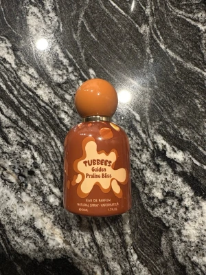 Golden praline bliss Tubbees - Säljer Tubees Golden Praline Bliss Eau de Parfum 50 ml som endast är använd en gång när jag provade den. Doften är en mjuk och söt gourmanddoft med inslag som påminner om praliner och vanilj, perfekt för dig som gillar varma, feminina och lite mysiga parfymer som fungerar både till vardag och kväll. Flaskan är i fint skick och den är i princip helt ny då den bara testats en gång.
