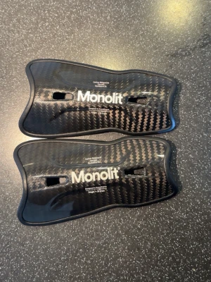 Monolit benskydd i kolfiber - Säljer ett par svarta benskydd från Monolit i kolfiber med ergonomisk form och väger bara 30 gram