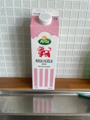Tom Arla Rosa Mjölk jordgubb 1L - En liter rosa mjölkdryck från Arla med smak av jordgubb. Förpackningen är rosa och vit med en tecknad ko på framsidan. Kartongen har skruvkork och är tillverkad i kartongmaterial.