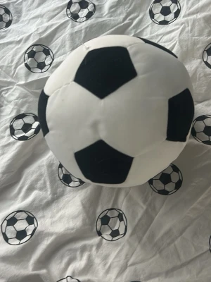 Mjuk fotboll i tyg - En svartvit mjuk fotboll i tyg, perfekt som leksak eller inredningsdetalj. Bollen har klassiskt mönster med svarta och vita fält och är rund i formen. Passar bra för både barnrum och vardagsrum.