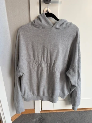 Grå hoodie från Acne Studios - Snygg grå hoodie från Acne Studios med tryck på ryggen där det står 'Acne Studios STOCKHOLM 1996'. Hoodien har huva, långa ärmar och ribbade muddar. Perfekt för en avslappnad och trendig look.