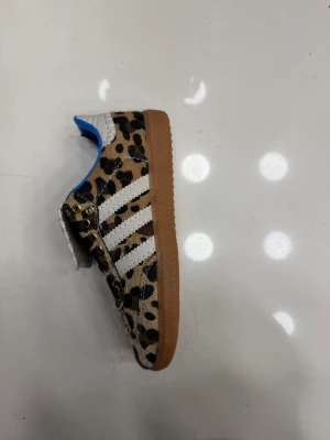 Adidas Wales Bonner leopardmönstrade sneakers(finns i storlek 37-40) - Unika sneakers från Adidas x Wales Bonner med leopardmönstrad ovandel, vita klassiska stripes och brun sula. Skon har blå insida och detaljer i vitt och brunt. Perfekt för dig som vill sticka ut med en cool och trendig look.