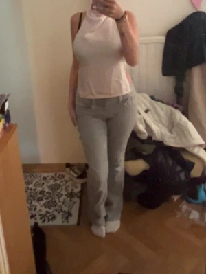 Vit/ ljusrosa ärmlös halterneck topp - Säljer en vit/ ljusrosa ärmlös halterneck topp med hög hals och öppen rygg. Toppen är croppad och har en clean, minimalistisk look som passar perfekt till jeans eller kjol. Materialet känns mjukt och lätt, troligtvis bomull eller polyester.