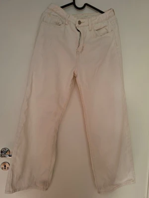 Vida vita jeans med raka ben - Säljer ett par vita jeans med raka ben och hög midja. Jeansen har klassisk femficksdesign och stängs med dragkedja och knapp. Perfekta för en clean och stilren look. Materialet är denim i bomull.