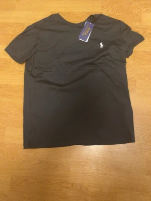 Svart t-shirt från Polo Ralph Lauren - Klassisk svart t-shirt från Polo Ralph Lauren med liten vit logga broderad på bröstet. T-shirten har rund halsringning och korta ärmar. Perfekt basplagg med stilren design.