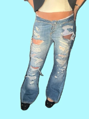 Blå slitna bootcut jeans - Midja: 38-39cm Innerbenslängd: 71cm. Tanken bakom denna look är att den övre delen av byxan viks, vi har valt att extra inte sy fast det, så man fortfarande har valet att vika upp dem om man vill 💕