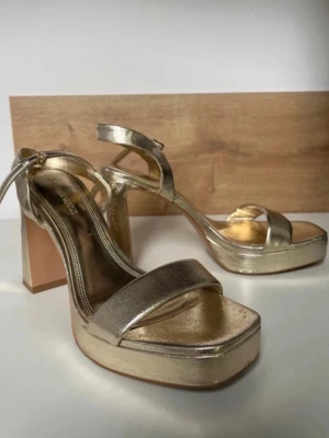 Guldiga klackar💛 - Säljer just nu dessa snygga guldiga blockheels i guld från Stradivarius. Skorna har en justerbar ankelrem och metallicfinish som ger en riktigt trendig look. Perfekta för för bal/sommar!! Köpta secondhand, endast provade av mig.🥰