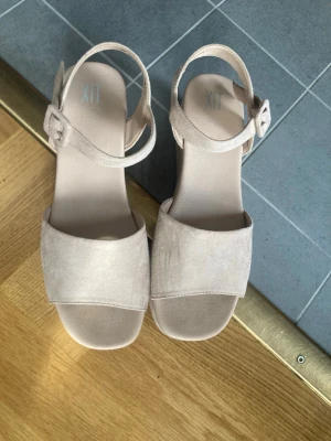 Beige platåsandaler - Supersöta beiga platåsandaler från XIT i storlek 37, köpta från Din Sko. Perfekt till sommaren eller om man vill vara lite extra fin 💗de har lite lätta slitningar längst bak på sulan (bild 4) De har även några repor på vänster sko som man ser på första bilden 💗