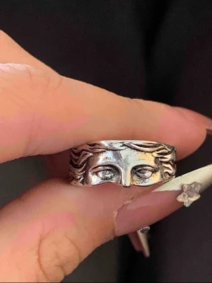 Silvrig ring med ansiktsmotiv - Cool silvrig ring med ett detaljerat ansikte i antik stil framtill. Ringen har en bred design och är tillverkad i metall med snygga skulpterade detaljer som ger en unik och konstnärlig vibe.