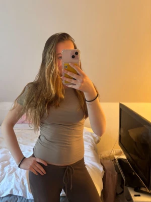 Beige tight kortärmad topp - Snygg beige topp med tight passform och korta ärmar. Toppen har en enkel, stilren design och är lätt att matcha med olika outfits. Perfekt för dig som gillar en basic men trendig look.