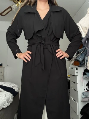 Svart trenchcoat med knytskärp - Stilren svart trenchcoat med bälte. Tunn. Från bikbok i storlek L.