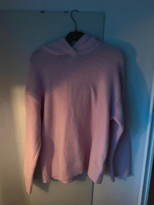 Ljusrosa hoodie från BikBok - Mysig ljusrosa hoodie från BikBok i stickad kvalitet. Hoodien har en avslappnad passform, ribbade muddar och en stor huva. Perfekt för dig som gillar en enkel men söt stil. Materialet känns mjukt och skönt mot huden.