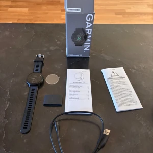 Garmin Forerunner 55 svart smartklocka - Säljer en Garmin Forerunner 55 smartklocka i svart med rund urtavla och silikonarmband. Klockan har en sportig design och levereras med originalkartong, laddkabel och manualer. Perfekt för dig som vill hålla koll på träning och hälsa. Knappast Andvänd då jag fick en ny klocka i student present 
