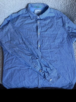 Scotch & Soda randig skjorta  – Strl M – Fint skick - Säljer en jättefin herrsskjorta från Scotch & Soda av modellen "Vacanza". Skjortan har ett snyggt, klassiskt blårandigt mönster och en skön, avslappnad känsla.  Storlek: M  Modell: Vacanza  Material: Skön och luftig bomullskvalitet  Skick: Mycket gott skick, fräsch och välvårdad.  Detaljer: Stilren design med fina designdetaljer som är typiska för Scotch & Soda. Perfekt för både sommarhalvåret och vardagsbruk.