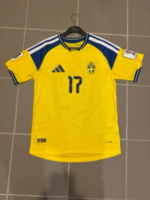 Gyökeres nr 17 - Gul och blå matchtröja från Adidas för Sveriges landslag, med nummer 17 och namnet Gyökeres på ryggen. Tröjan har korta ärmar, broderad landslagssköld och tryckta detaljer. Tillverkad i lätt och ventilerande material, perfekt för fotboll.
