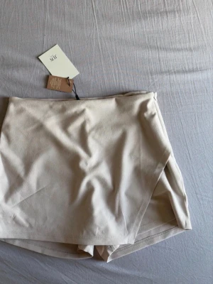 Beige skorts från JDY - Supersnygg beige skorts från JDY. Har en mjuk och stretchig känsla, perfekt för dig som vill ha både stil och komfort. Materialet är tunt och följsamt, och färgen är lätt att matcha med allt.